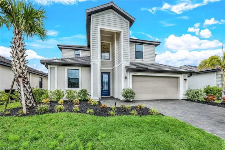 View of front of property with a garage and a front lawn