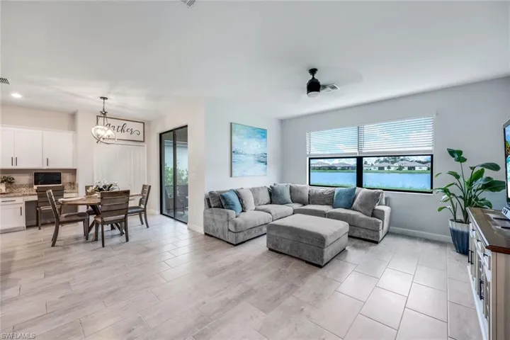Living room with light tile flooring and ceiling fan with notable chandelier