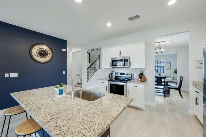 Kitchen with sink, white cabinets, a center island with sink, and stainless steel appliances