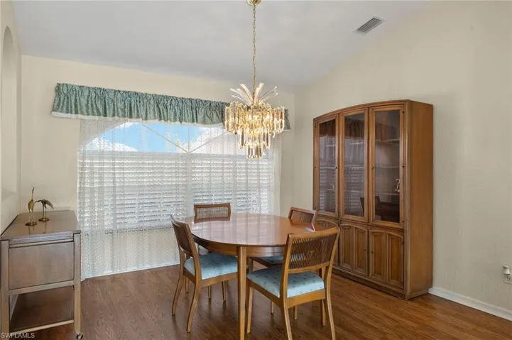 Dining space featuring a chandelier, large bright windows and laminate flooring.