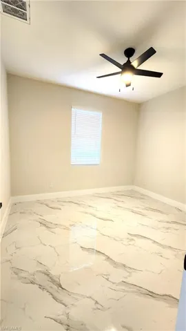 Bedroom featuring light marble finish floors and a ceiling fan