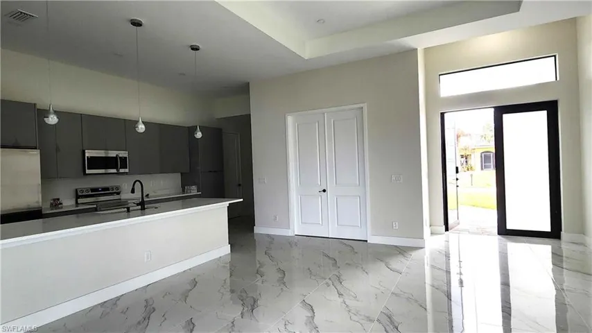 Kitchen featuring gray cabinetry, modern cabinets, pendant lighting, stainless steel appliances, and light countertops