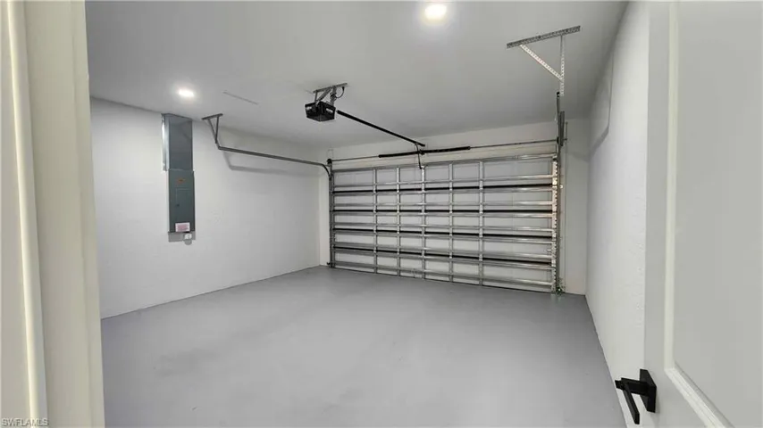 2 car Garage with electric panel, recessed lighting, and a garage door opener