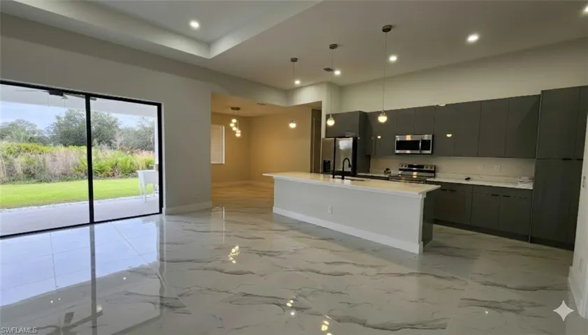 Kitchen with an island with sink, stainless steel appliances, modern cabinets, open floor plan, and a chandelier