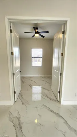 Den with light marble finish flooring and ceiling fan