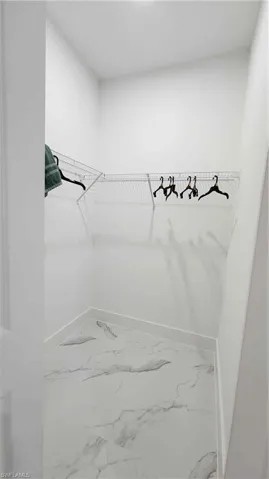 Walk in closet featuring light marble finish floors