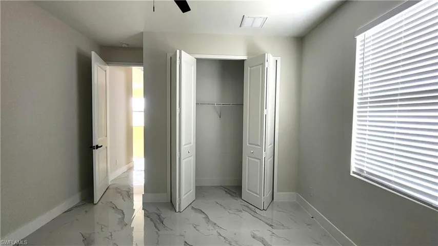 Guest bedroom with light marble finish flooring, a closet, and a ceiling fan