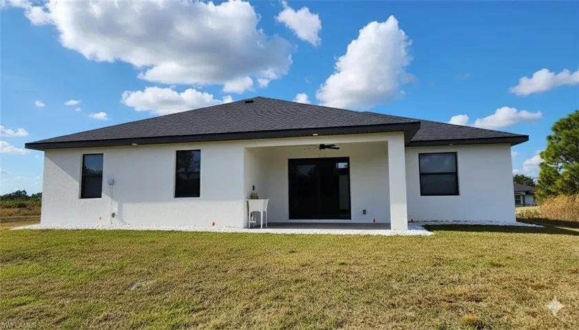 Back of house featuring a lawn, a ceiling fan, stucco siding, and a patio