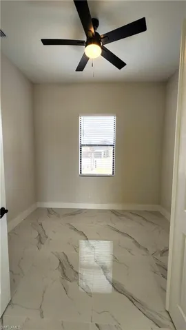 Den featuring a ceiling fan and light marble finish floors