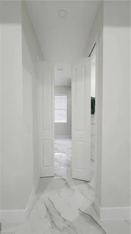 Hall with his and hers walk in closet baseboards and recessed lighting