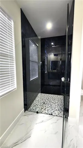 Full bath featuring a marble finish shower and marble finish flooring