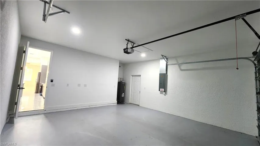 2 car Garage featuring electric panel, a textured wall, and electric water heater