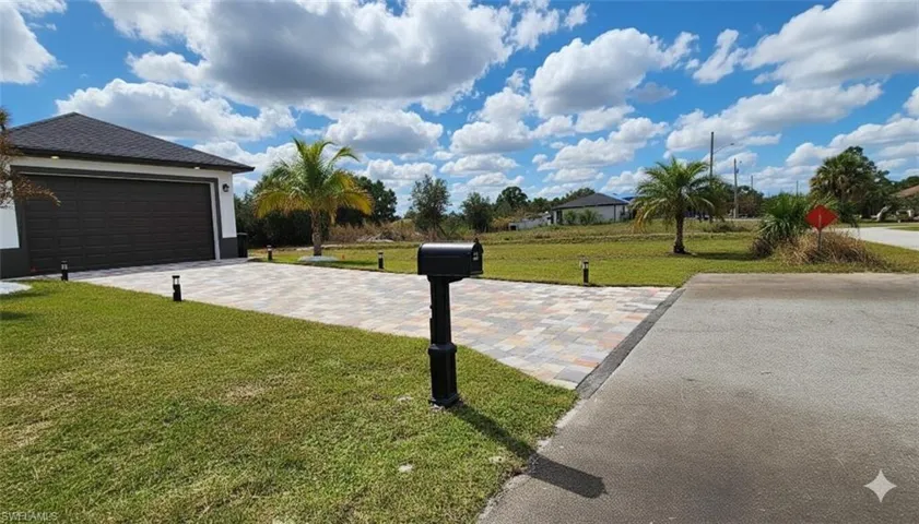 View of grassy yard with a garage and driveway