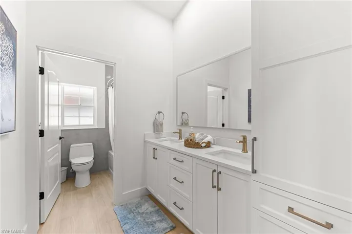 Bathroom featuring double vanity, light wood finished floors, and shower / bath combination with curtain