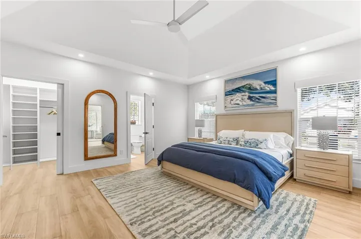 Bedroom featuring a walk in closet, light wood finished floors, recessed lighting, ceiling fan, and ensuite bath