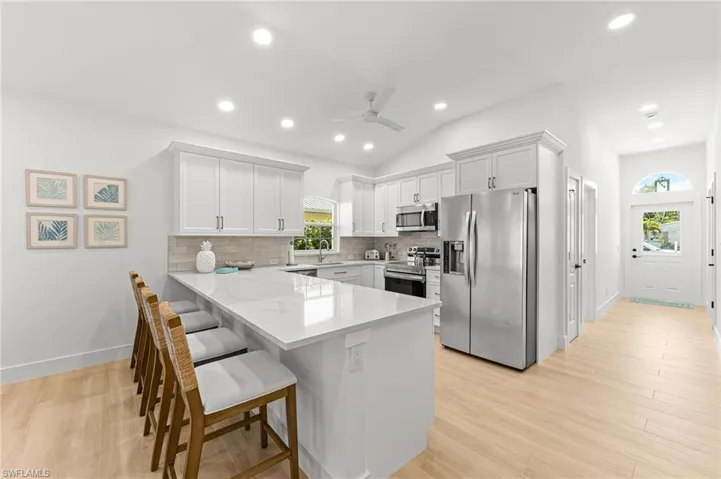 Kitchen with stainless steel appliances, white cabinetry, a peninsula, a breakfast bar area, and tasteful backsplash
