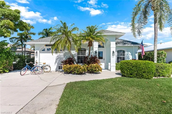 View of front of home featuring a front lawn, stucco siding, a shingled roof, concrete driveway, and an attached garage