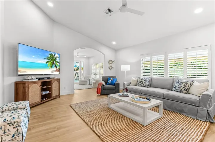 Living room with ceiling fan, arched walkways, light wood finished floors, and recessed lighting