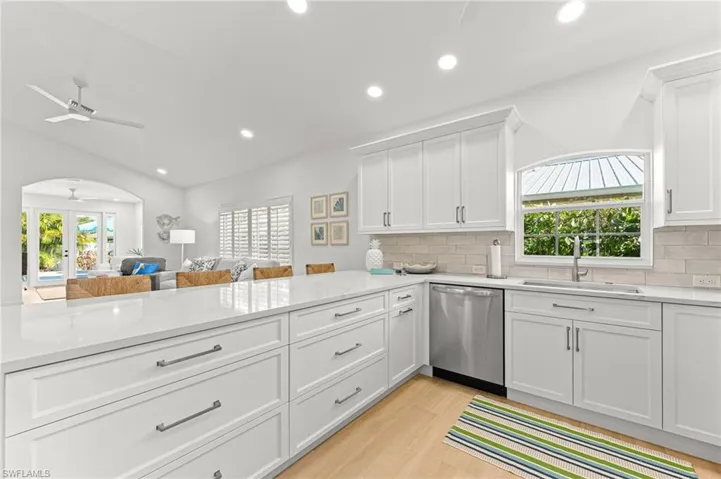 Kitchen with white cabinetry, recessed lighting, light stone countertops, stainless steel dishwasher, and arched walkways