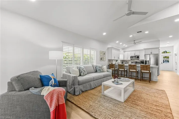 Living area featuring vaulted ceiling, recessed lighting, light wood finished floors, and ceiling fan