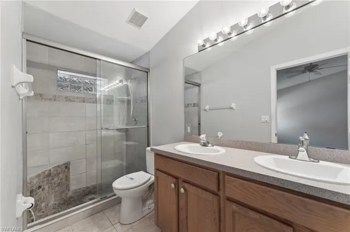 Bathroom with tile patterned floors, a sink, visible vents, and a stall shower