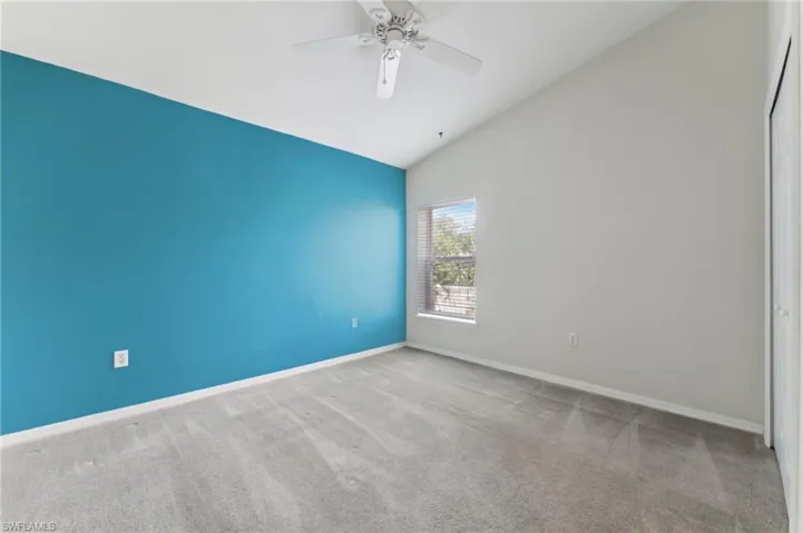 Spare room featuring lofted ceiling, carpet floors, a ceiling fan, and baseboards