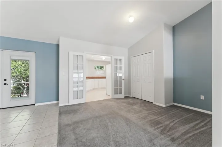 Unfurnished bedroom with carpet floors, french doors, tile patterned floors, and baseboards