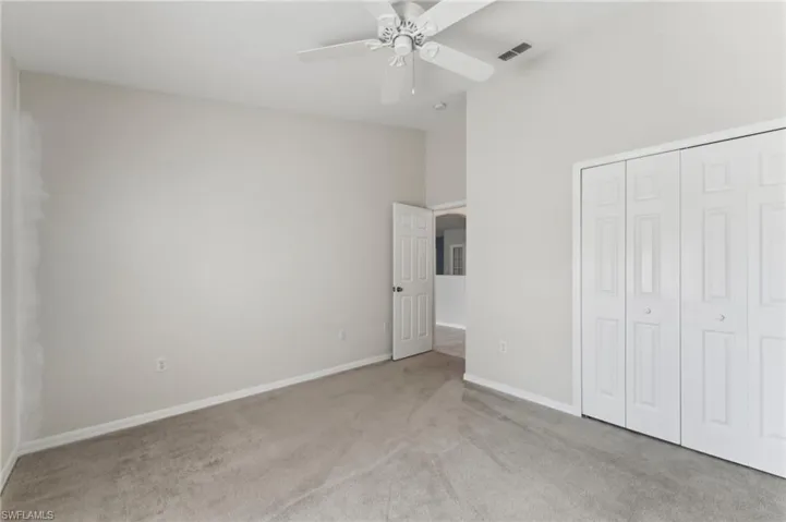 Unfurnished bedroom with baseboards, visible vents, light colored carpet, a closet, and ceiling fan