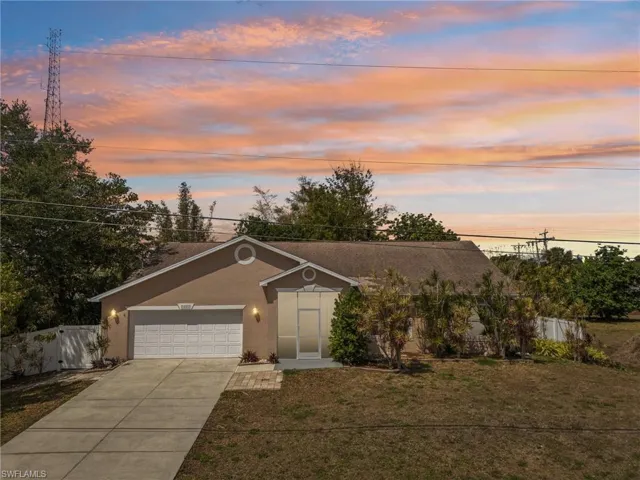 View of front facade featuring fence, stucco siding, an attached garage, driveway, and a front yard
