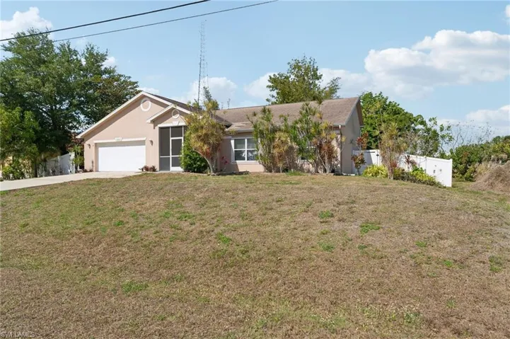 Ranch-style house featuring a front lawn, concrete driveway, fence, a garage, and stucco siding