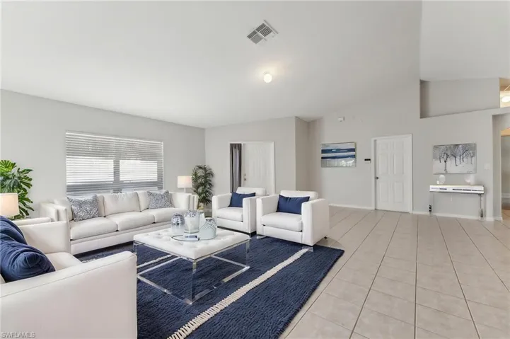 Virtually State Living area featuring baseboards, vaulted ceiling, visible vents, and light tile patterned floors