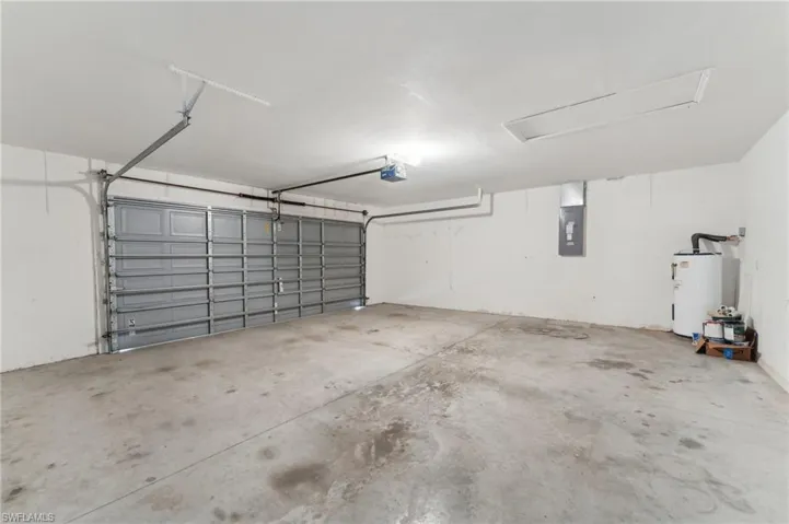Garage featuring electric panel, water heater, and a garage door opener