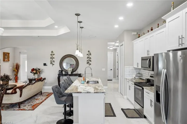 Kitchen with stainless steel appliances, light stone counters, a kitchen bar, open floor plan, and tasteful backsplash