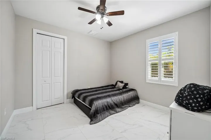 Bedroom #4 featuring light marble finish floors, a closet, and a ceiling fan