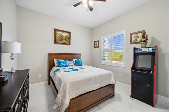 Bedroom #2 with light marble finish floors and a ceiling fan