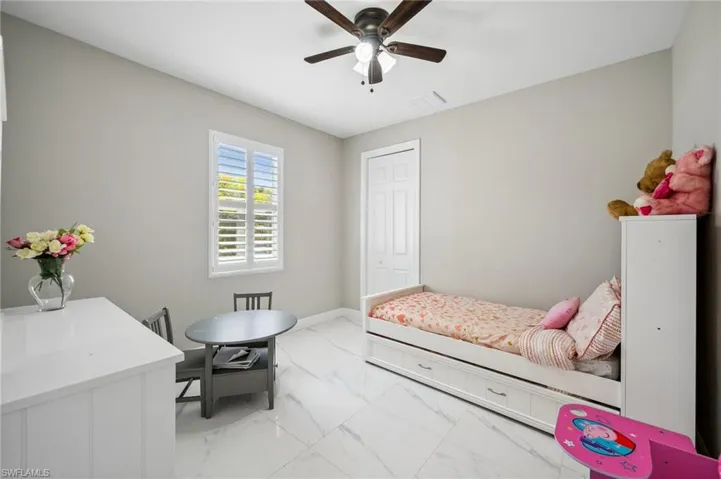 Bedroom #3 with light marble finish floors, a ceiling fan, and a closet