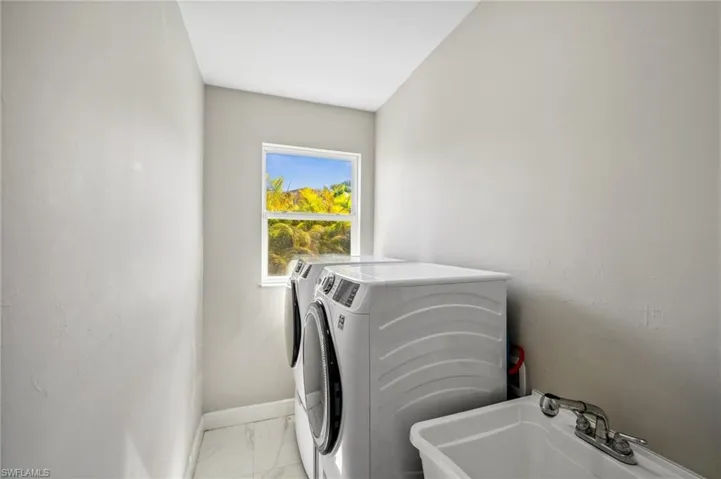 Laundry room featuring independent washer and dryer and light marble finish floors