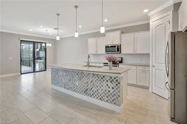 Kitchen featuring appliances with stainless steel finishes, a sink, light countertops, white cabinetry, and decorative backsplash