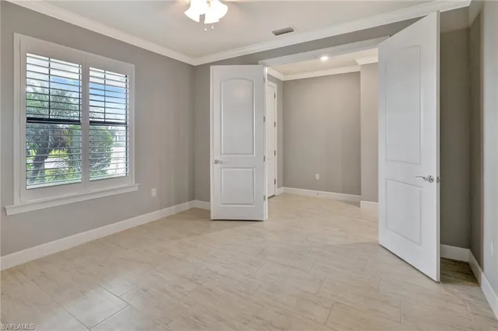Unfurnished bedroom featuring visible vents, ornamental molding, baseboards, and multiple windows