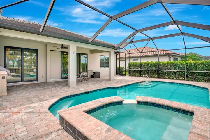 View of pool featuring a lanai, a pool with connected hot tub, a ceiling fan, and a patio area
