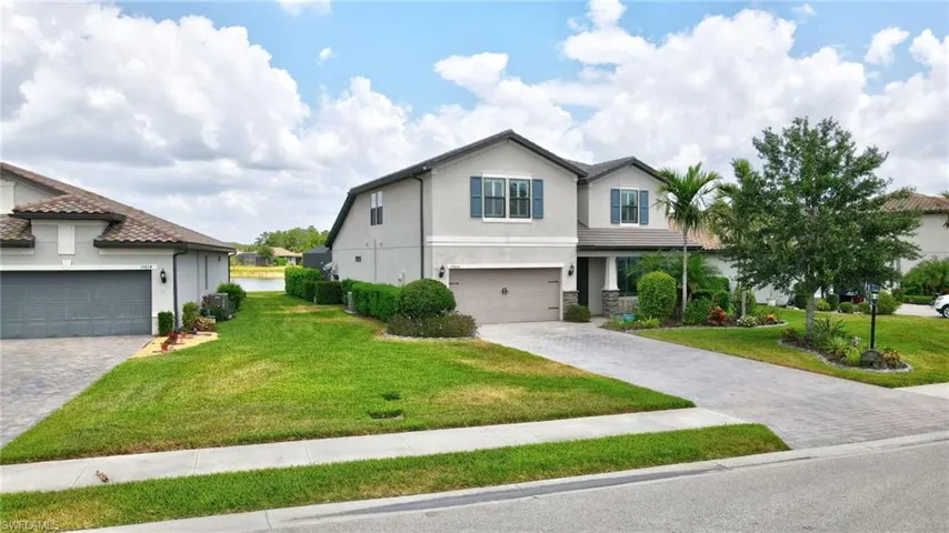 View of front of property featuring decorative driveway, stucco siding, and a front yard