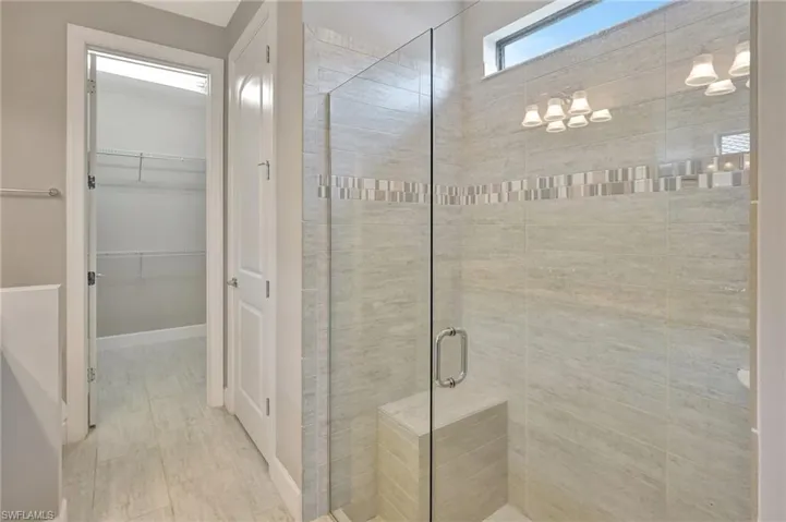 Bathroom with a walk in closet and a shower stall