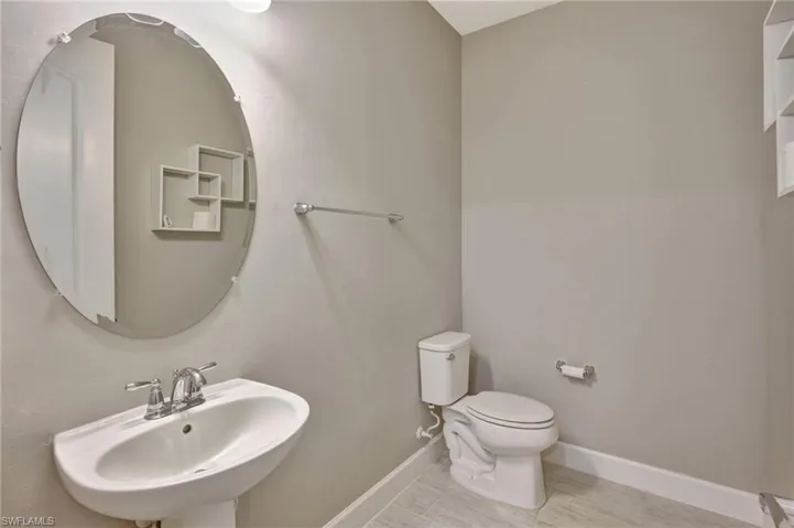 Half bathroom featuring a sink, baseboards, and toilet