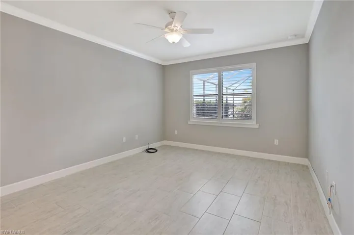 Empty room featuring crown molding, a ceiling fan, and baseboards