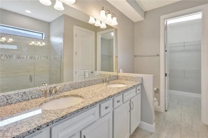 Bathroom with double vanity, a sink, baseboards, and a stall shower