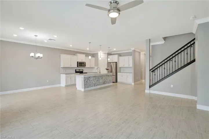 Unfurnished living room with crown molding, recessed lighting, a sink, and ceiling fan with notable chandelier