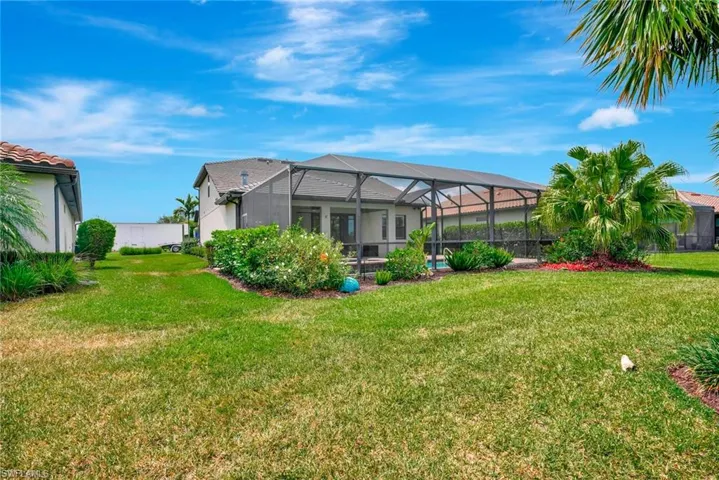 Back of house featuring a lanai, stucco siding, and a yard
