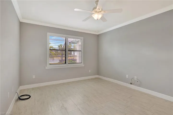 Spare room with ceiling fan, ornamental molding, baseboards, and wood finished floors