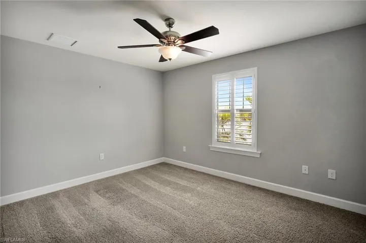 Carpeted empty room featuring baseboards, ceiling fan, and visible vents