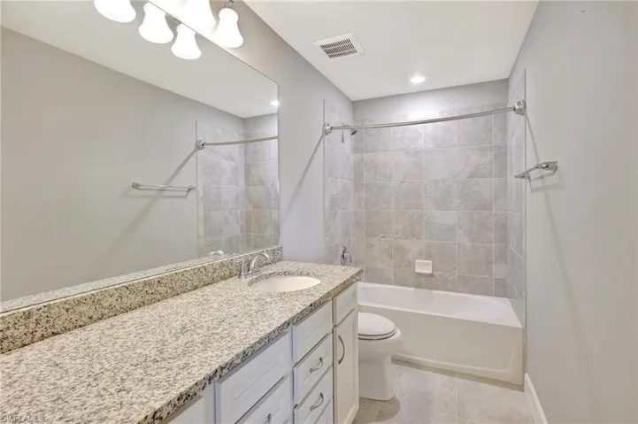 Full bath featuring visible vents, vanity, toilet, shower / tub combination, and tile patterned floors